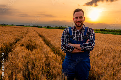 The farmer poses for a photo in the wheat field, proud of his hard work and the bountiful harvest. The golden wheat surrounds him, creating a picturesque backdrop for the photograph.