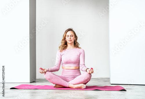 Slim woman training yoga poses, asanas in pink tight-fitting tracksuit in fitness gym. Stretching, pilates practice. Workout, back exercises at home on fitness mat. Private lessons, personal trainer