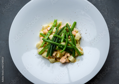 Delicate gnocchi paired with fresh salmon and green beans, served on a clean white plate in a simple yet elegant culinary presentation