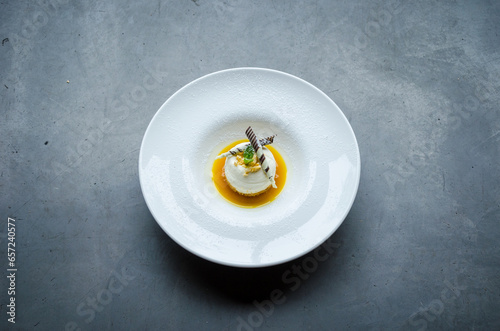 Creamy white chocolate mousse topped with caramel sauce and decorative garnishes, elegantly served on a white plate for a sophisticated dessert