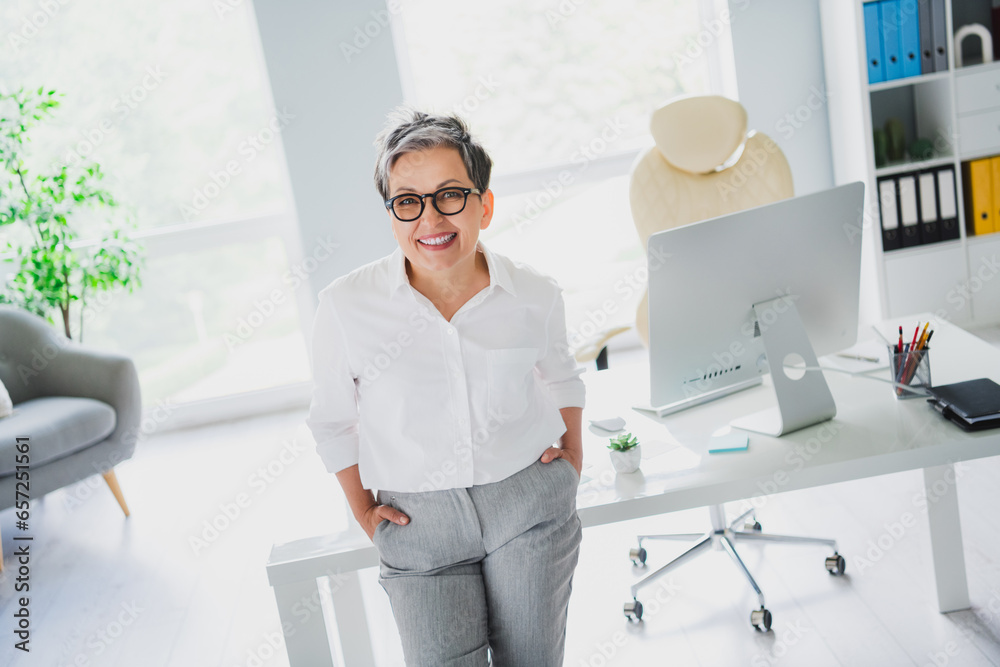 Photo of positive happy lady leader wear white shirt smiling indoors workplace workstation