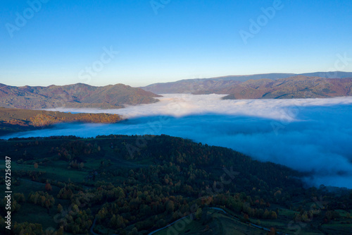 Flying above the clouds in dawn. Misty morning in the valley, aerial view