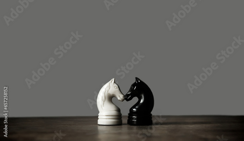 Vintage chess pieces, black and white knight on dark gray background. Chess sports wallpaper. Minimalism. Copy space photo
