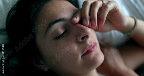 Tired woman waking up in the morning, close-up face looks at camera