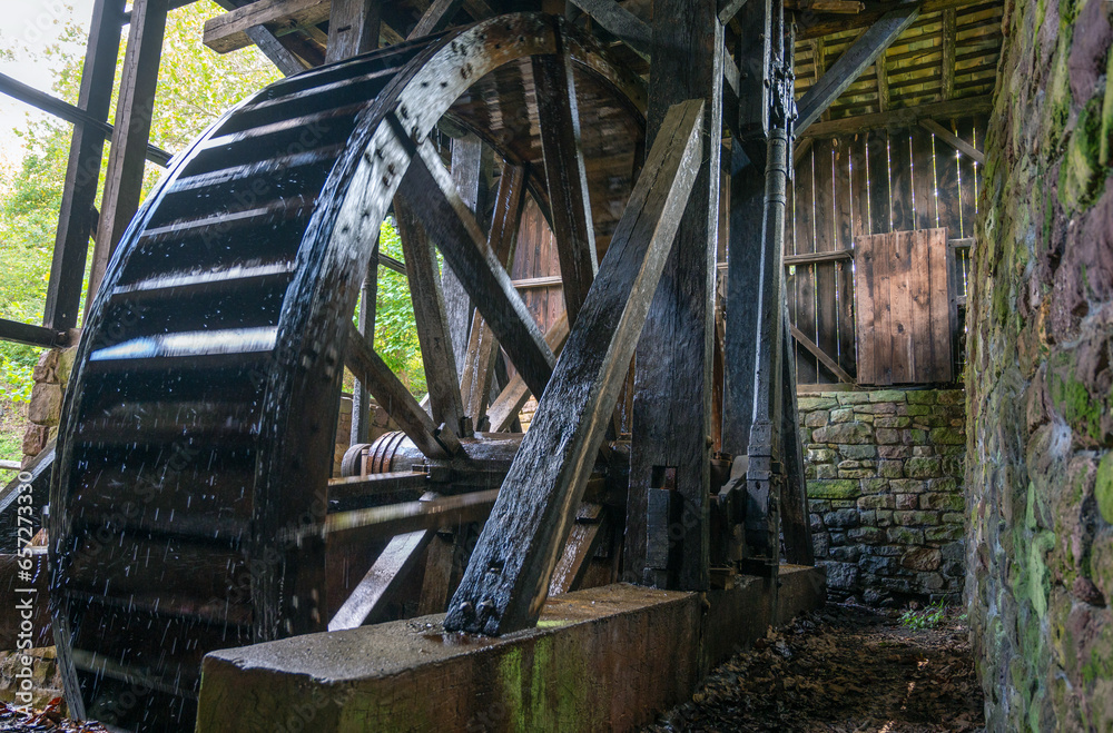 Giant colonial American hydro power wooden water wheel with mechanism and spokes visible inside stone machine house Hopewell 
Furnace Pennsylvania