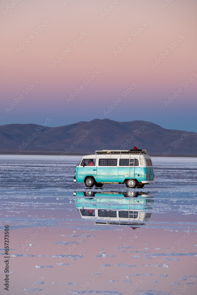 Perfect reflection of a classic van on a salt flat with water at sunset