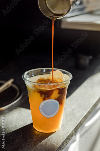 Bumble cold iced refreshing coffee drink with orange juice in the making