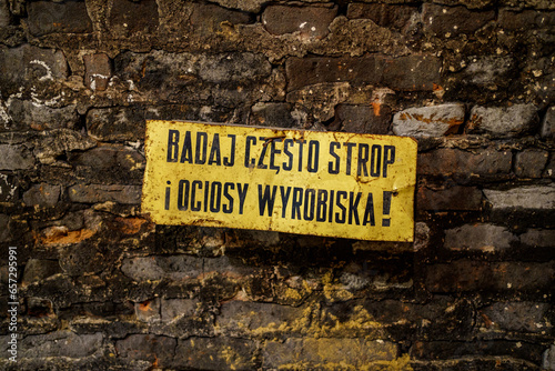 A warning sign in Polish in an underground corridor: examine the ceiling and sides of the excavation frequently!