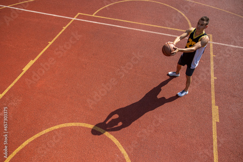 Male sportsman playing basketball throwing ball at playground. © zinkevych