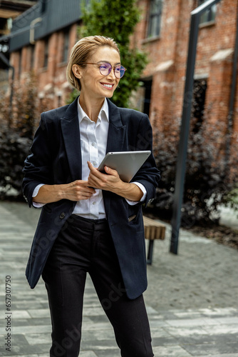 Cute young woman in black suit with a tablet in hands photo