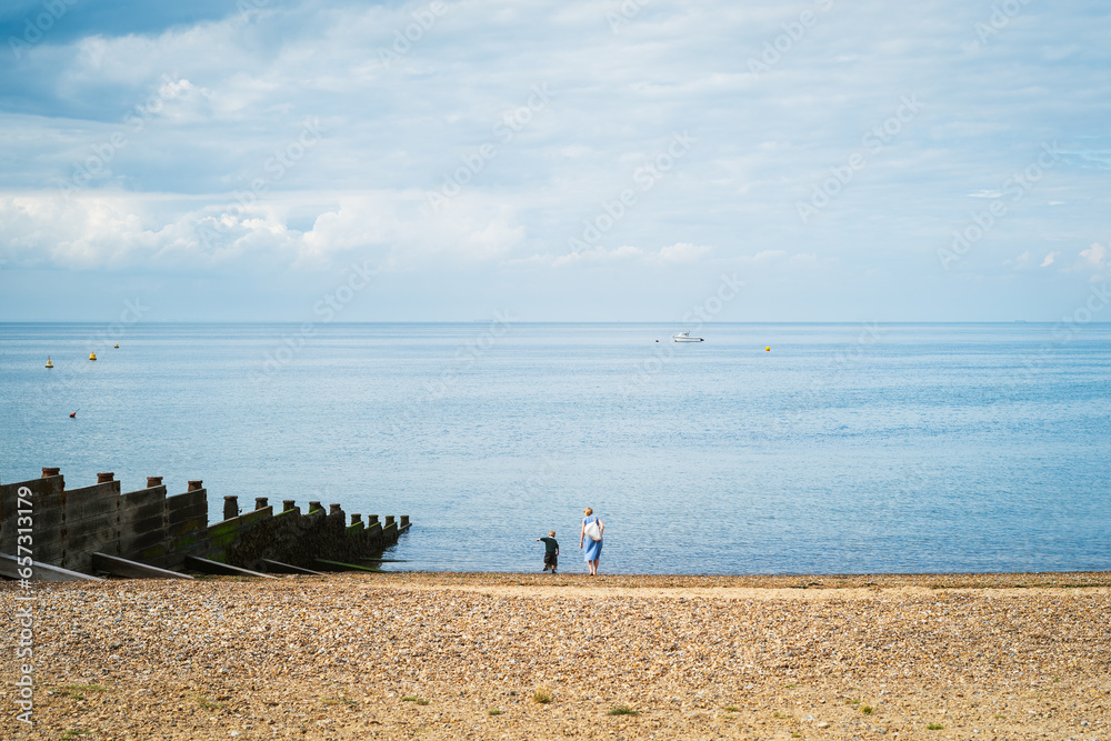 Φωτογραφία Whitstable beach with a wooden groyne and a woman and small boy at the edge of the water
