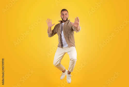 Cheerful millennial caucasian guy with beard in casual has fun, jumping, freezes in air photo