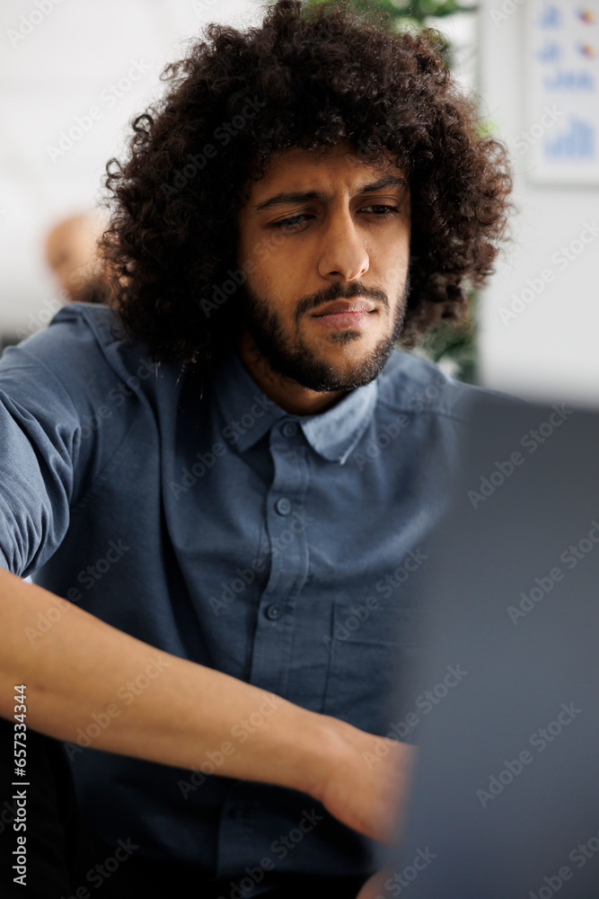 Young arab financial analyst analyzing statistics on laptop in business office. Company executive manager working at product promotional campaign and checking sales report Young arab financial analyst analyzing statistics on laptop in business office. Company executive manager working at product promotional campaign and checking sales report
