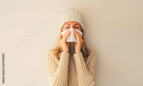 Vászonkép Sick upset woman sneezing blow nose using tissue wearing warm soft knitted cloth