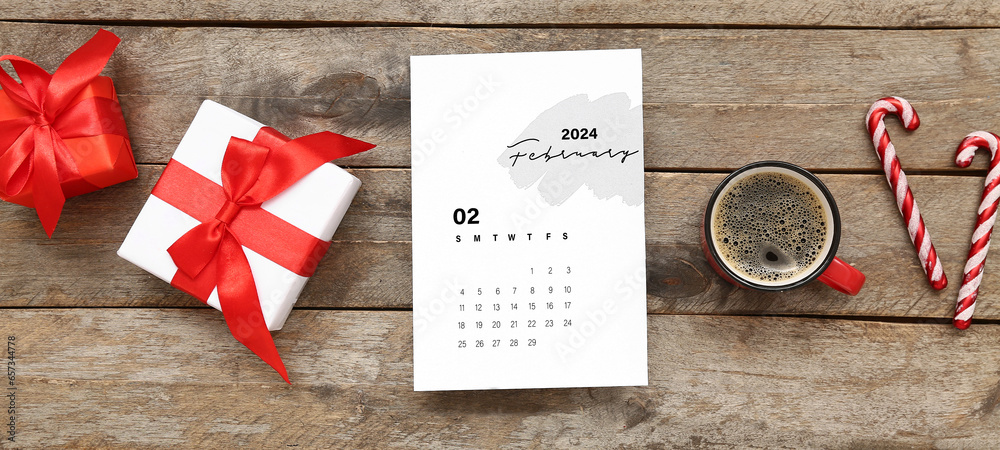 Paper calendar for February 2024 with gift boxes, candy canes and cup of coffee on wooden background - obrazy, fototapety, plakaty 