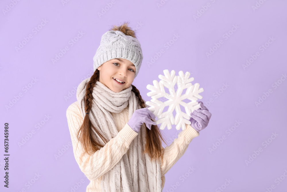 Cute little girl in winter clothes with big snowflake on lilac background Cute little girl in winter clothes with big snowflake on lilac background