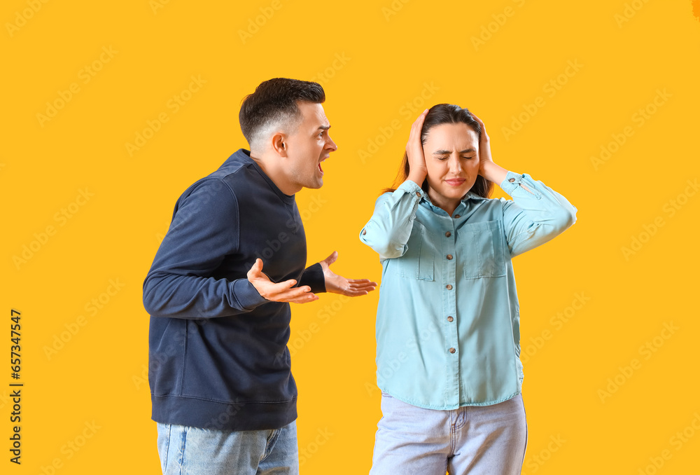 Young couple quarreling on yellow background Young couple quarreling on yellow background