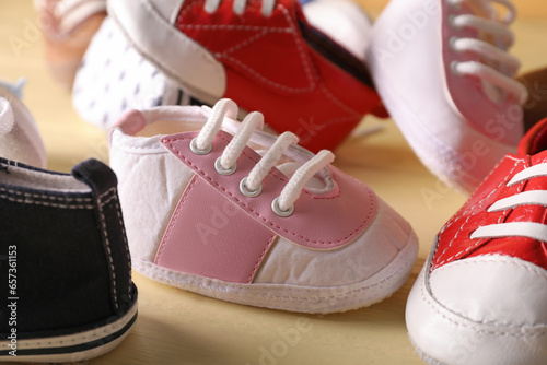 Different baby booties on color wooden background, closeup