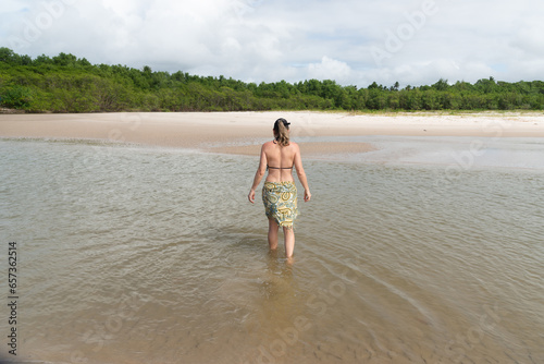 A beautiful Caucasian woman crossing the river to the other bank. Taquari Beach in Valenca, Brazil. photo