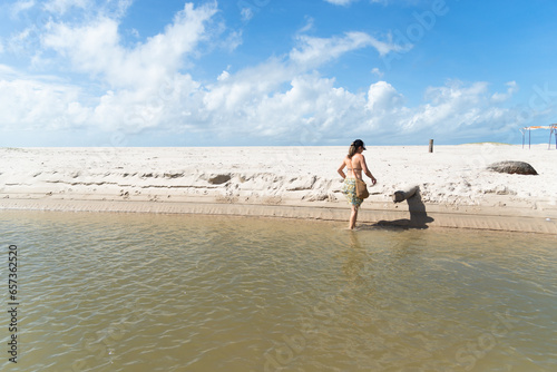 A beautiful Caucasian woman crossing the river to the other bank. Taquari Beach in Valenca, Brazil. photo