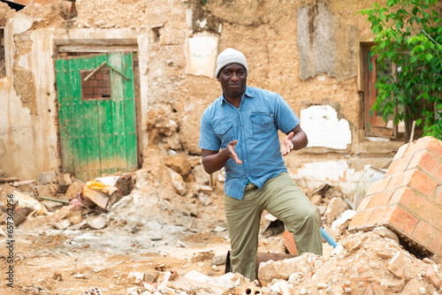 The adult afro man standing near old ruin abandoned building