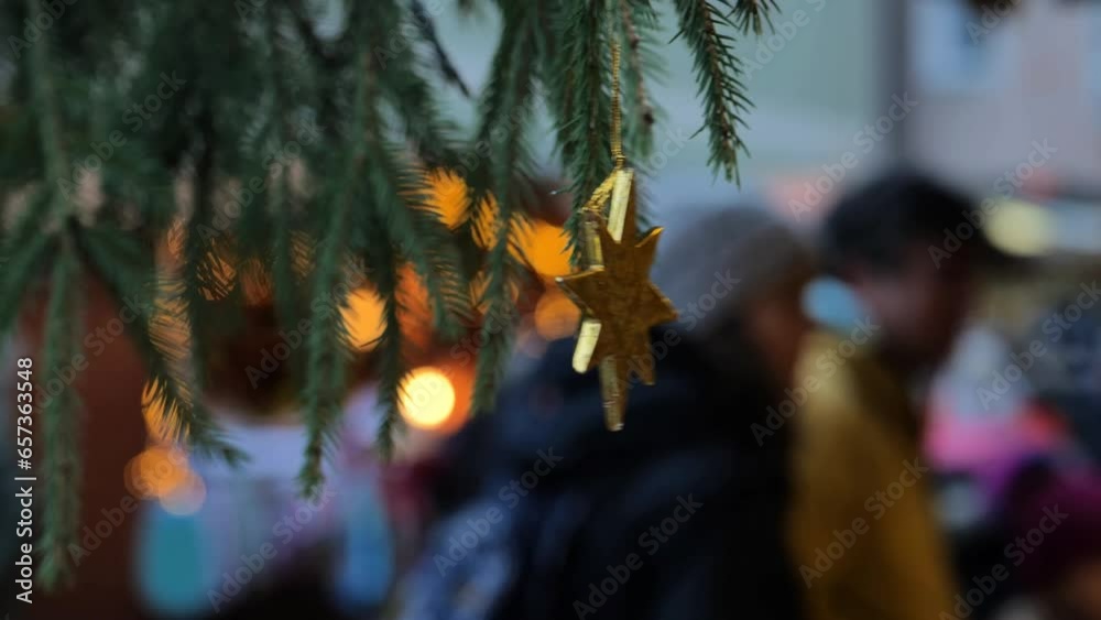 Christmas market.Golden star on spruce branches and people at the Christmas evening market.Soft blurry focus. Christmas time in Europe. 4k footage