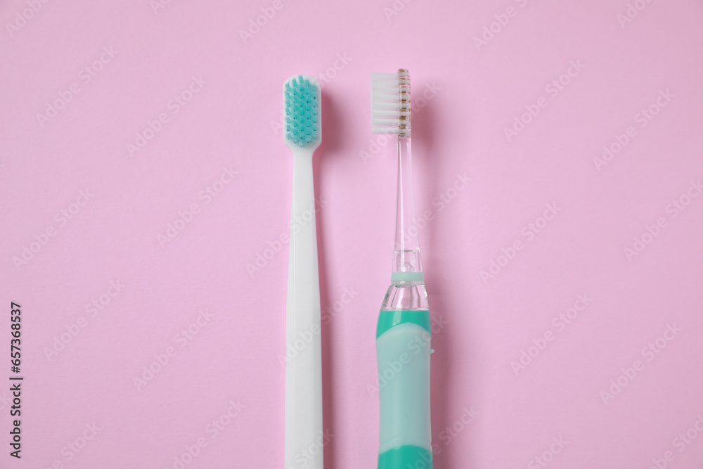 Electric and plastic toothbrushes on pink background, flat lay