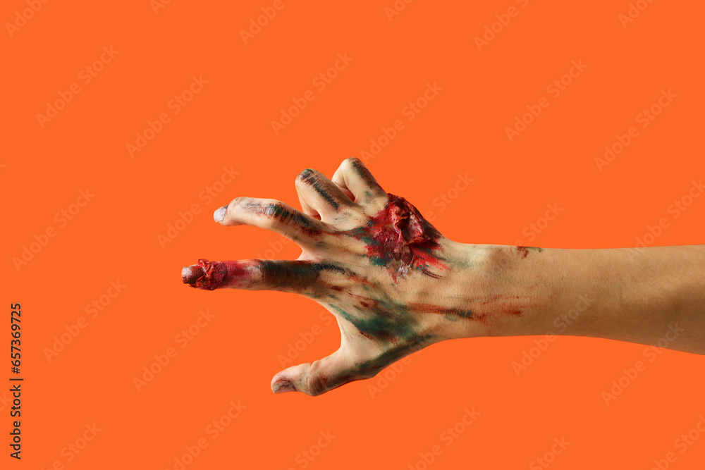 Fototapeta premium Zombie hand on orange background. Halloween celebration