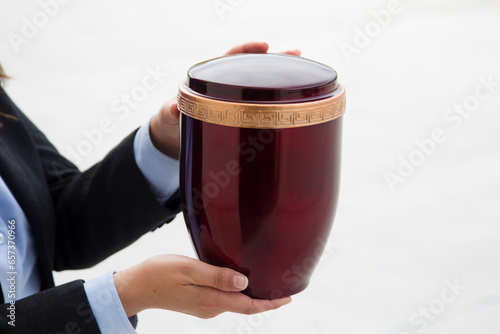 Funerary urn held by two hands on white background photo