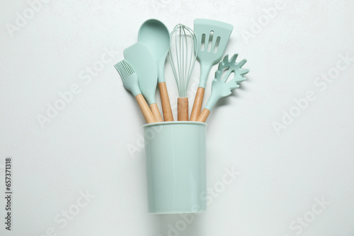 Set of kitchen utensils in holder on white table  top view