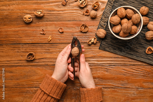 Woman cracking walnuts on wooden background