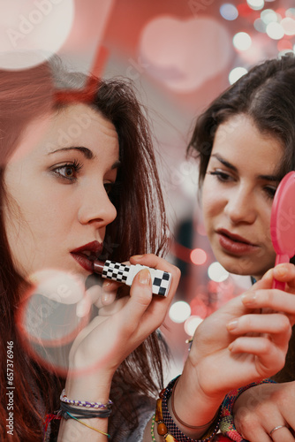 Young women applying makeup, readying for club night photo