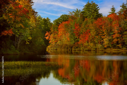  autumn sunny day on the lake. Reflection of autumn trees in the water and soft sunlight.