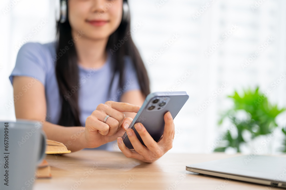 A woman typing on her smartphone, using her smartphone while sitting at a table indoors. A woman typing on her smartphone, using her smartphone while sitting at a table indoors.