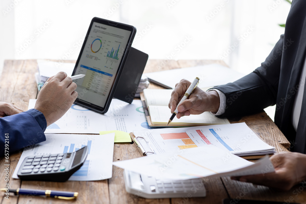 Group of confident business people point to graphs and charts to analyze market data, balance sheet, account, net profit to plan new sales strategies to increase production capacity. Group of confident business people point to graphs and charts to analyze market data, balance sheet, account, net profit to plan new sales strategies to increase production capacity.