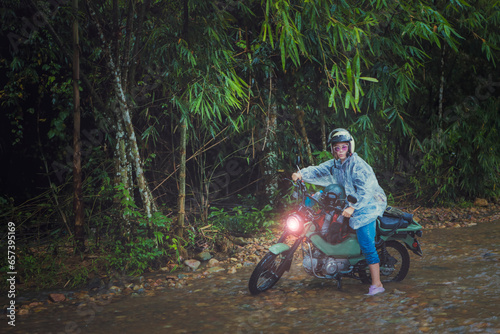 pretty woman riding small enduro motorcycle crossing shallow creek © stockphoto mania
