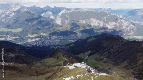 Cinematic aerial of alps mountain top with old wooden chapel on steep peak. Beautiful alpine scenery with valley and town below landscape view. Kellerjoch, Austria. Drone flying around summit, orbit photo