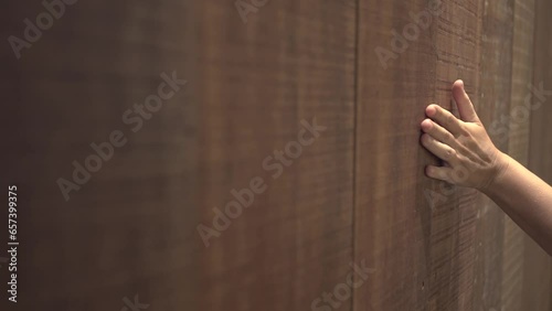 Close-up of a woman's hand touching a wooden wall surface