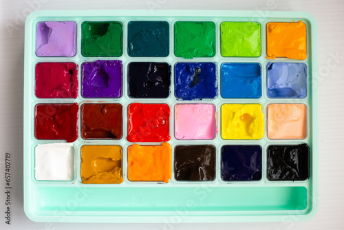 different bright colors of gouache paint in its case