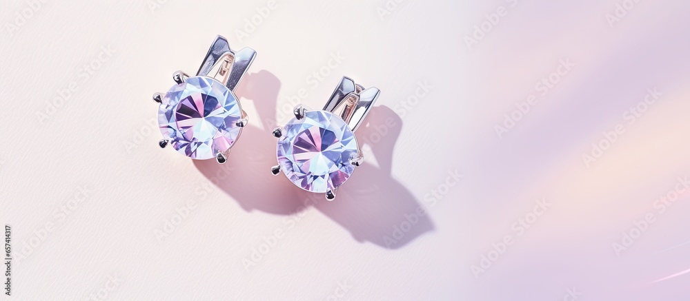 Silver sapphire earrings on a isolated pastel background Copy space with hinged lock Silver sapphire earrings on a isolated pastel background Copy space with hinged lock