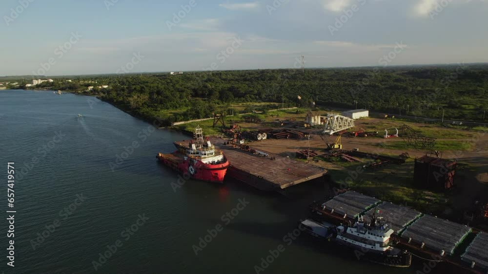 A tanker unloading its cargo on a shipyard near a river at sunset. A tanker unloading its cargo on a shipyard near a river at sunset.