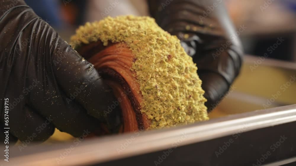 Pistachio croissant donut being covered in pistachio pieces side view Pistachio croissant donut being covered in pistachio pieces side view