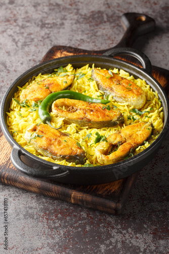 Fragrant and delicious Ilish Pulao is a signature Bengali-style Pilaf cooked with Hilsa Fish closeup on the plate on the table. Vertical