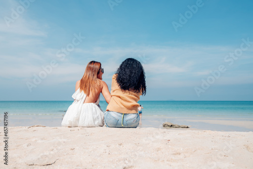 Happy couple woman in bikini sitting and playing together on the beach having fun in a sunny day, Beach summer holiday sea people concept.