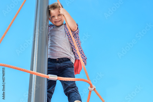 portrait of a joyful child, boy, preschooler, schoolchild with a backpack on the playground against a background of blue sky close-up