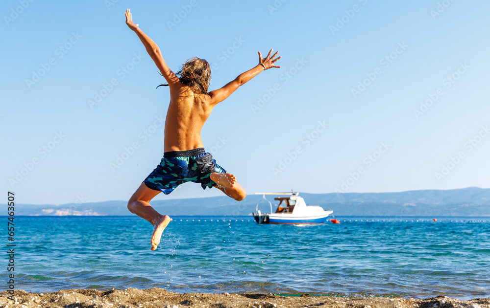 Young boy,  happy child jumping in the air on the beach- vacation, happiness, travel destination concept