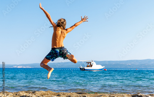 Young boy, happy child jumping in the air on the beach- vacation, happiness, travel destination concept