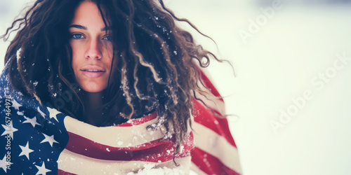 Evocative blonde hippie draped in American flag amidst falling snow, embodying freedom and nature with a muted, chilly color palette. photo