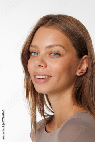 Beautiful young girl with fresh healthy skin. Woman advertise ear-rings. White background. Earrings, ear caffs closeup. Blond european woman with long hair with big lips, pretty smile. Cosmetology photo