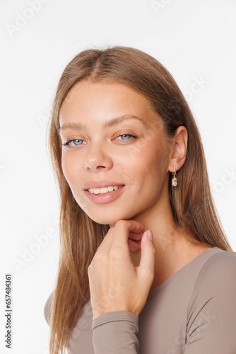 Beautiful young girl with fresh healthy skin. Woman advertise ear-rings. White background. Earrings, ear caffs closeup. Blond european woman with long hair with big lips, pretty smile. Cosmetology
